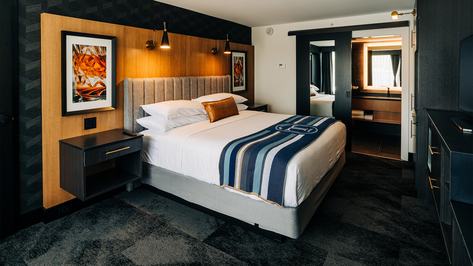 a bed with a striped blanket and a mirror in a hotel room