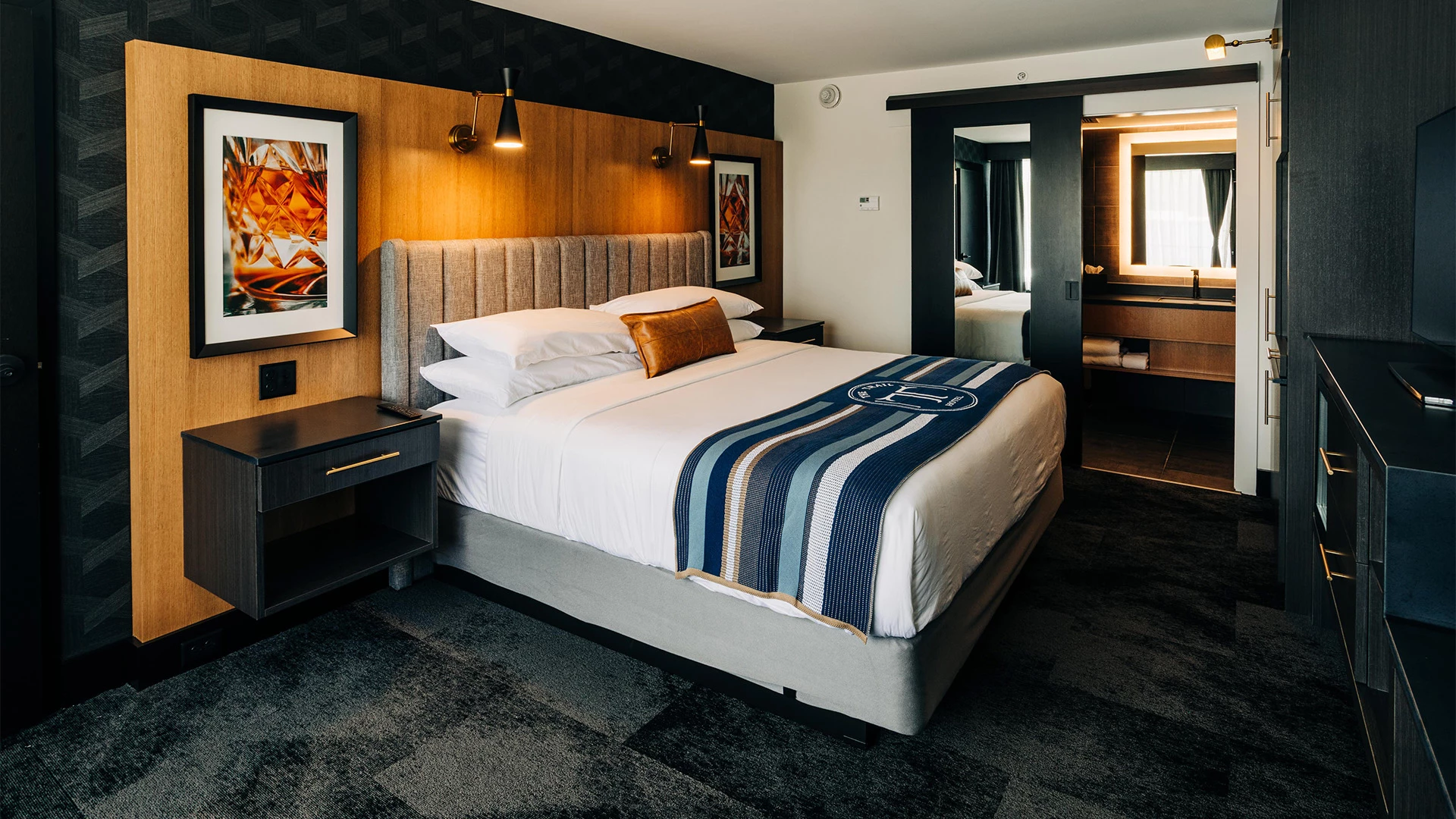 a bed with a striped blanket and a mirror in a hotel room