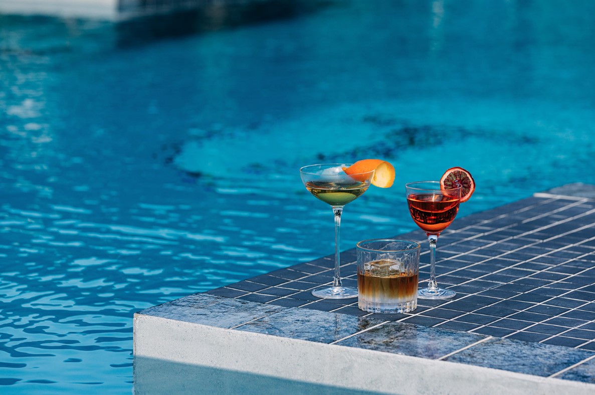 a group of glasses of drinks on a pool edge