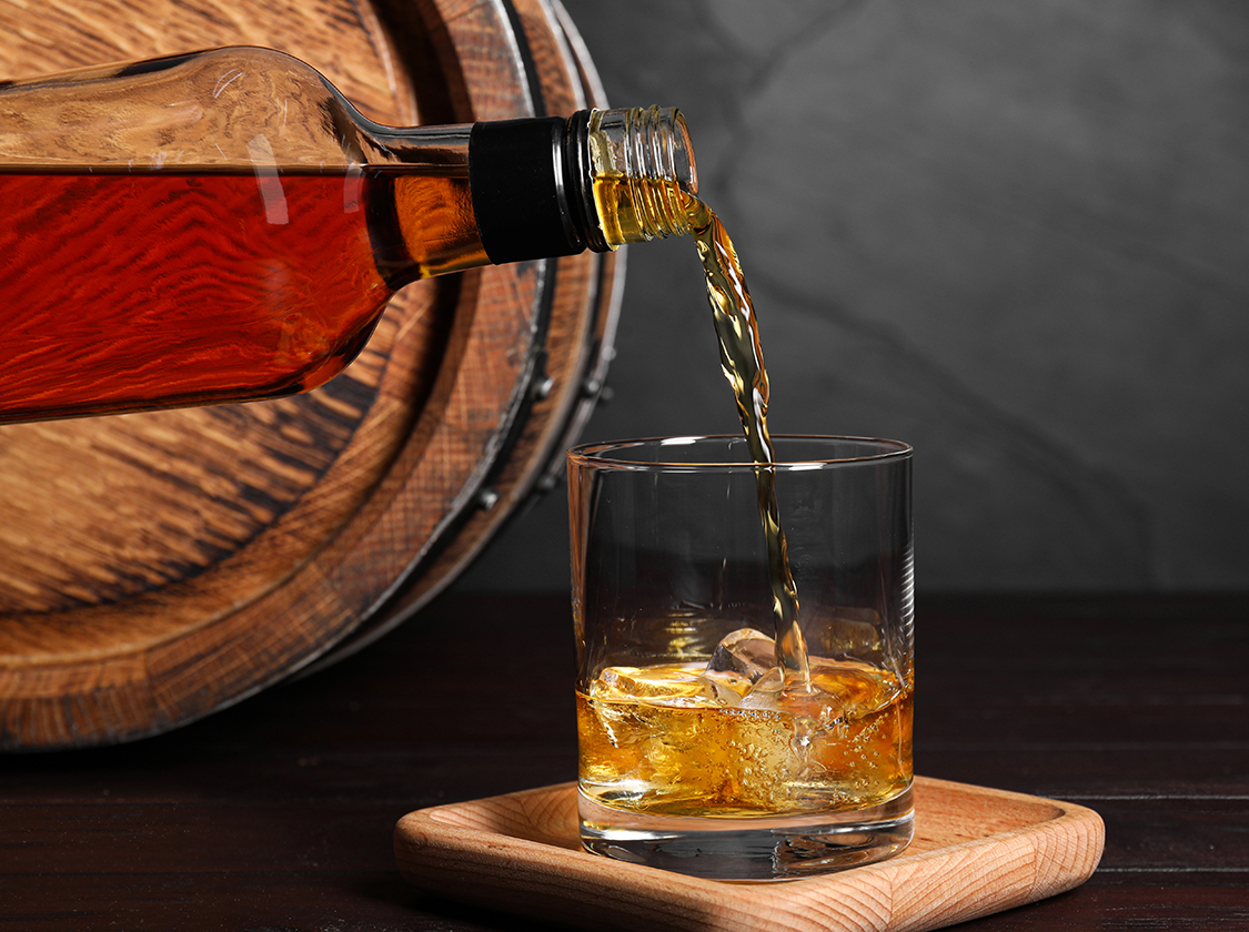 a bottle pouring amber liquid into a glass