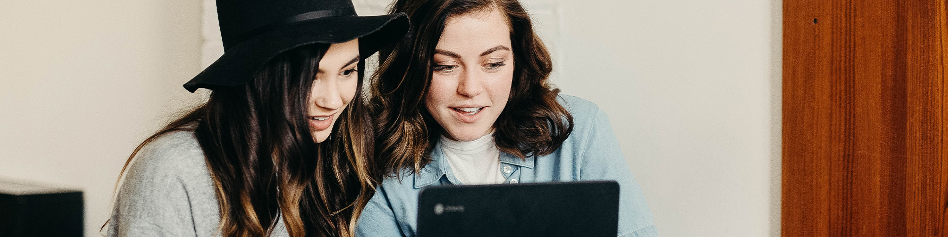 a couple of women looking at a laptop