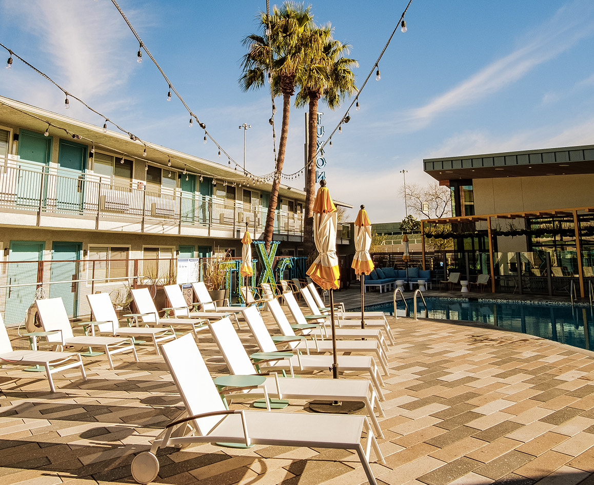 a patio with chairs and umbrellas by a pool