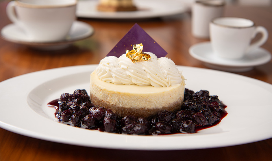 a cheesecake with a piece of whipped cream and berries on a white plate