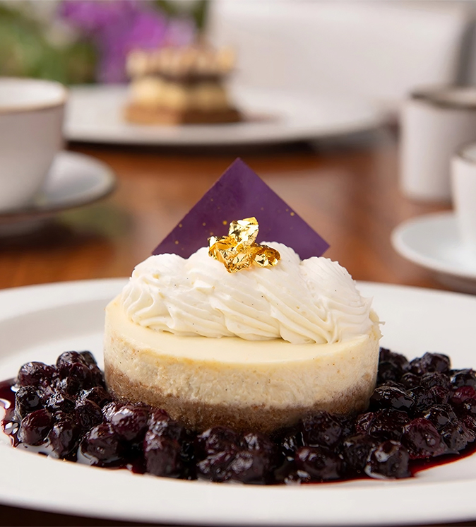 a cheesecake with a purple square on top and blueberry sauce