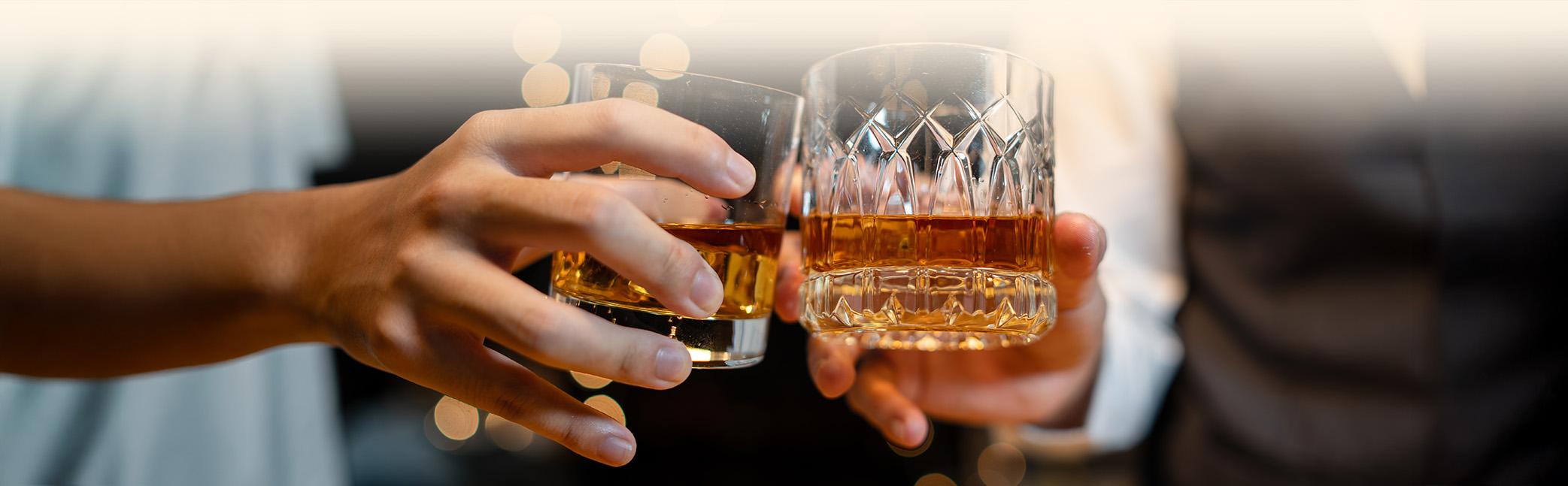 a pair of hands holding glasses with liquid in them
