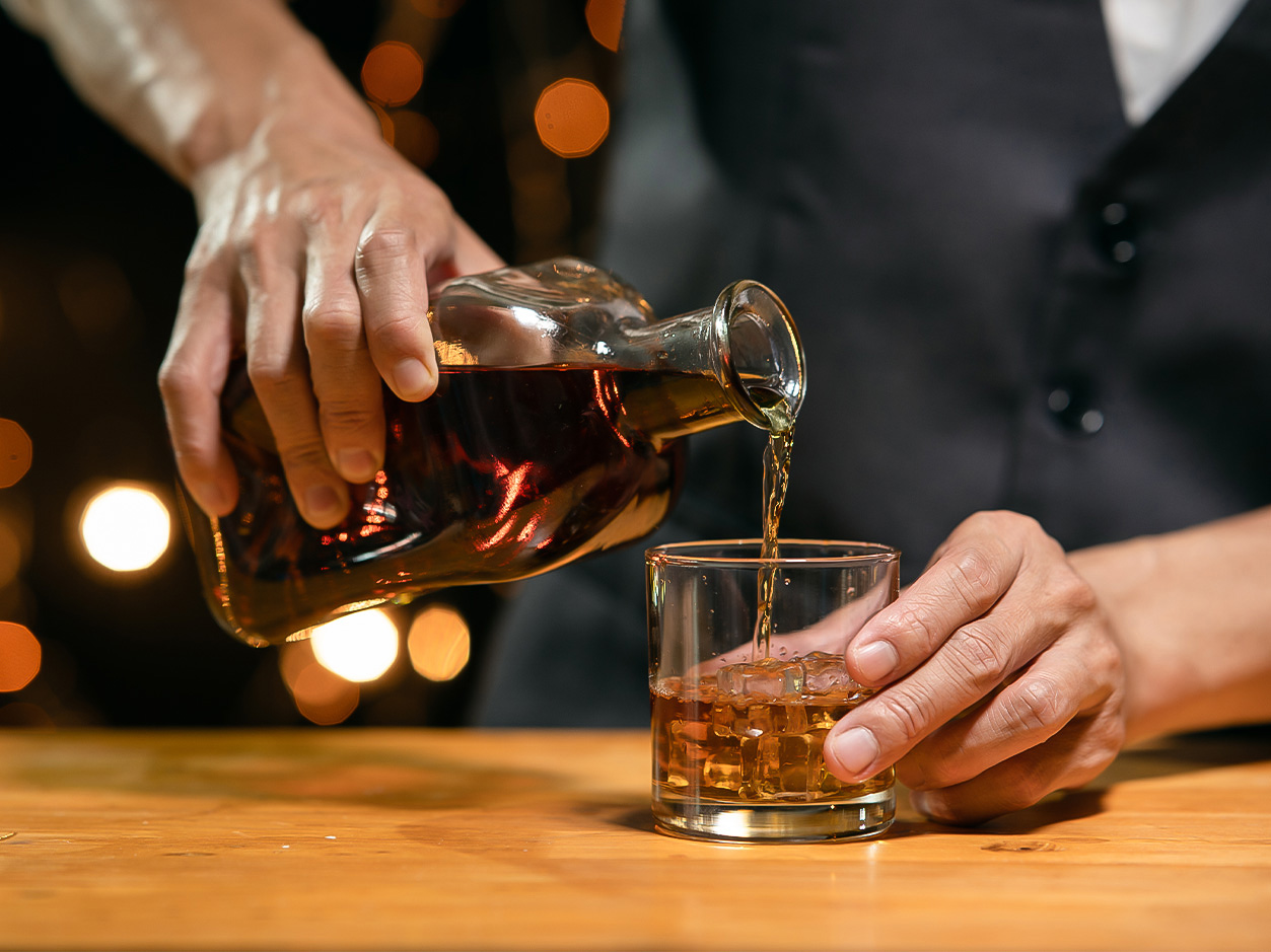 a person pouring a drink into a glass