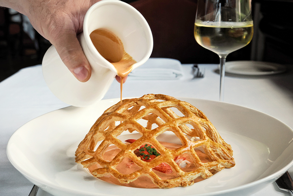 a hand pouring sauce on a plate of food