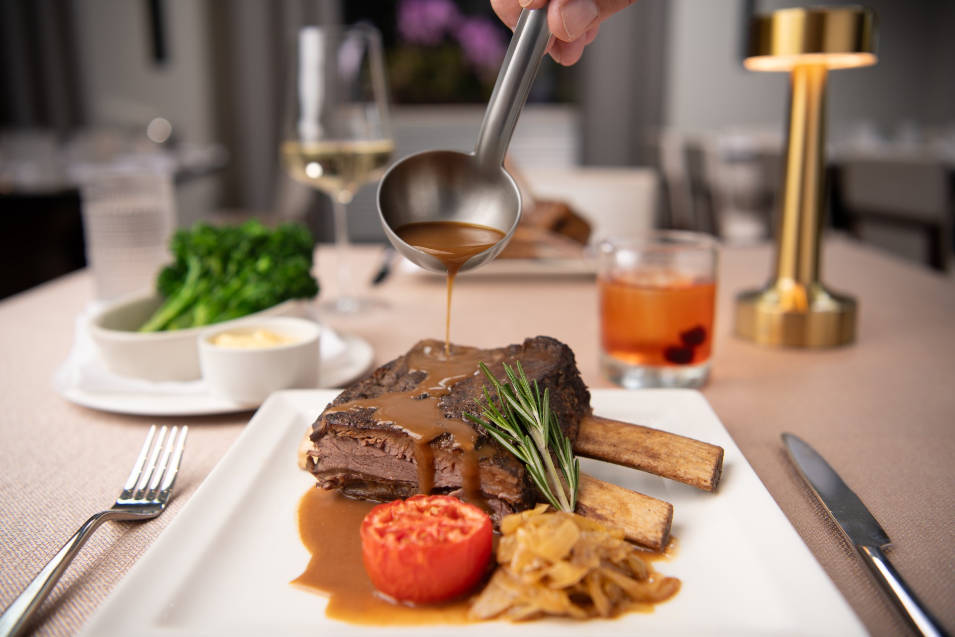a person pouring gravy on a plate of meat