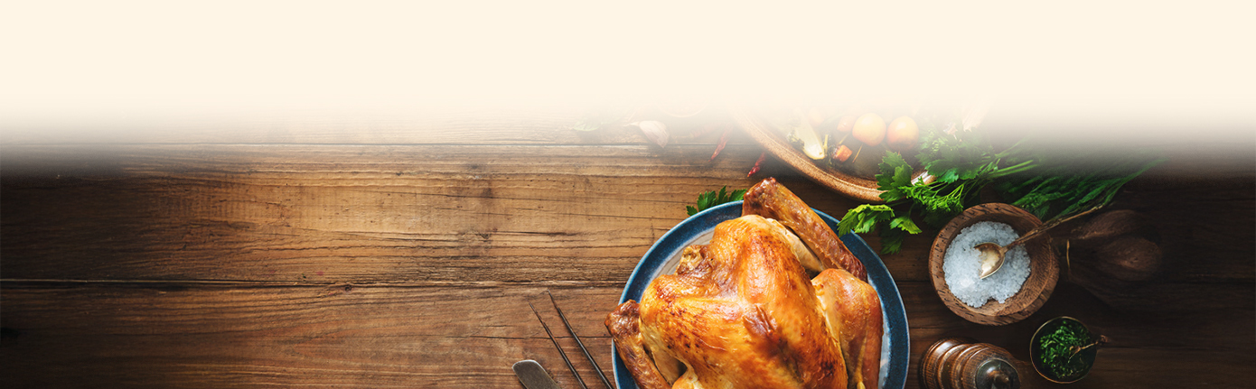 a whole roasted chicken on a blue plate next to a bowl of vegetables