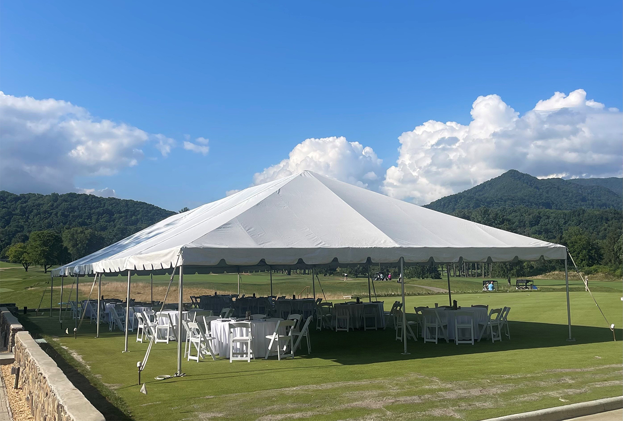 a white tent with tables and chairs on a lawn
