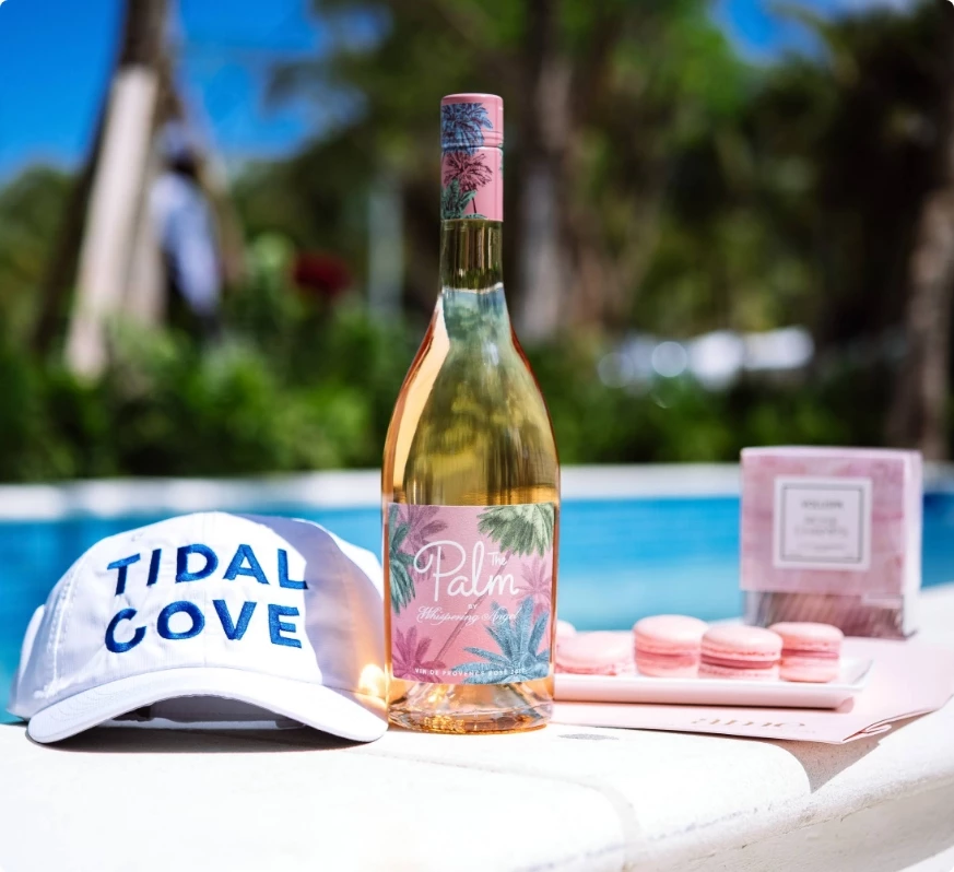 a bottle of wine and a hat by a pool