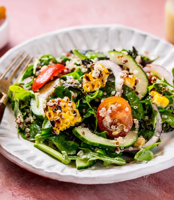 a plate of salad with corn and quinoa