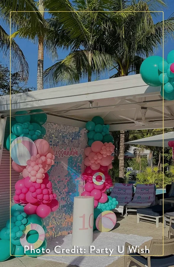 a balloon decorations outside with palm trees and a pool