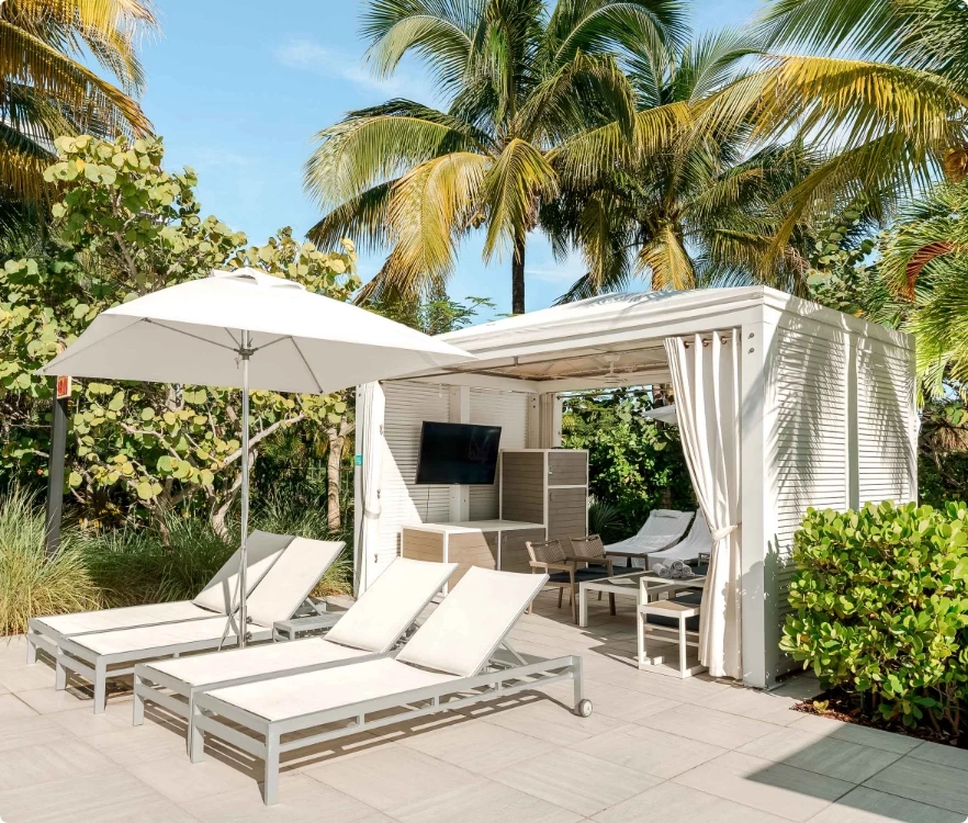 a white structure with chairs and umbrellas on a patio