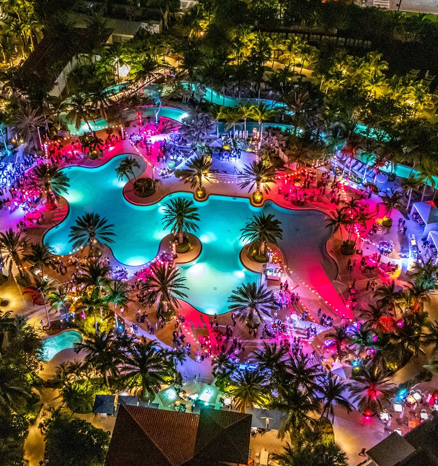 an aerial view of a pool with people and trees