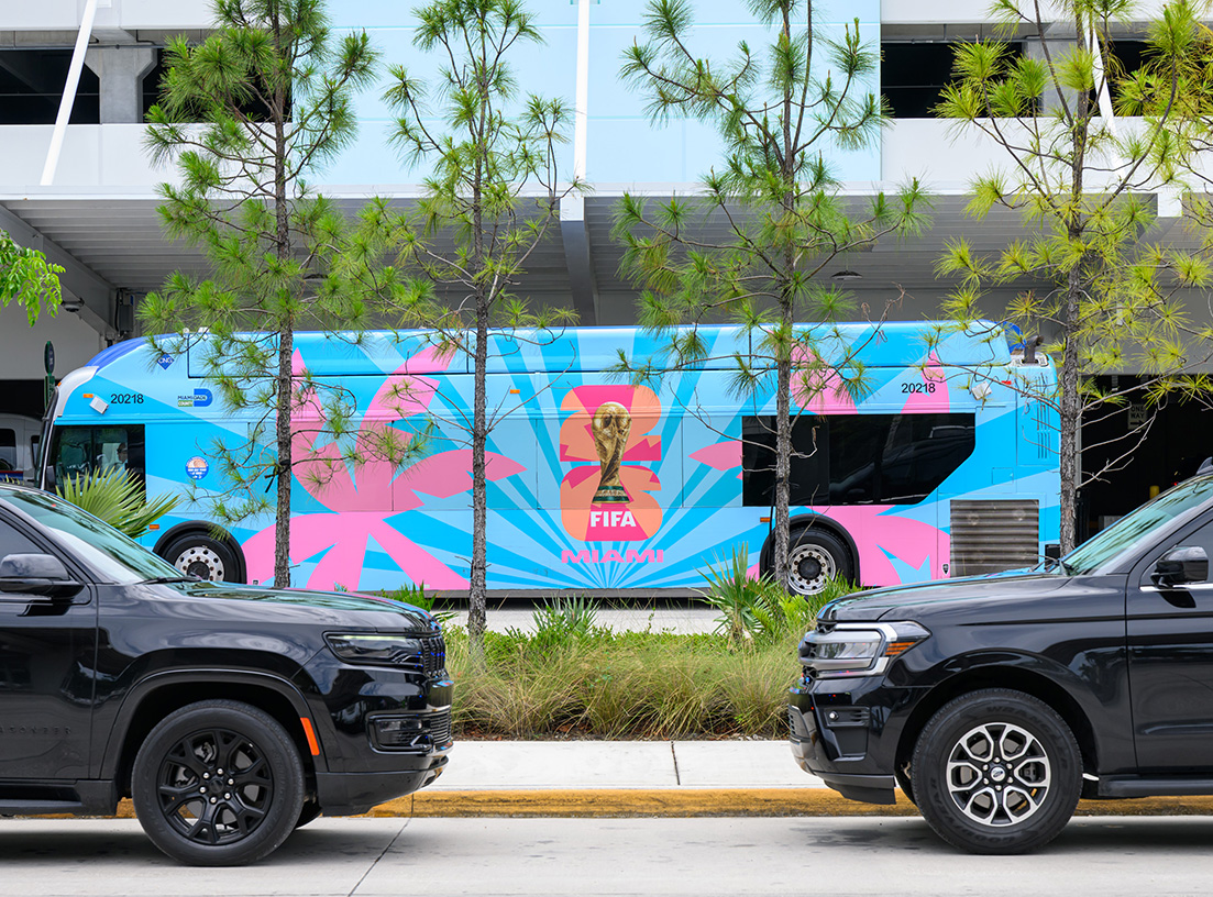 a blue bus parked next to a black truck