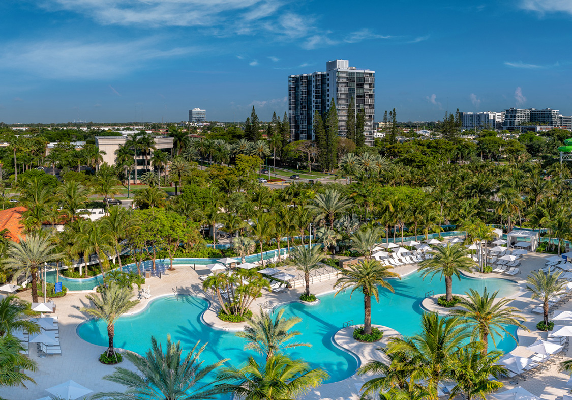a pool with palm trees and buildings in the background