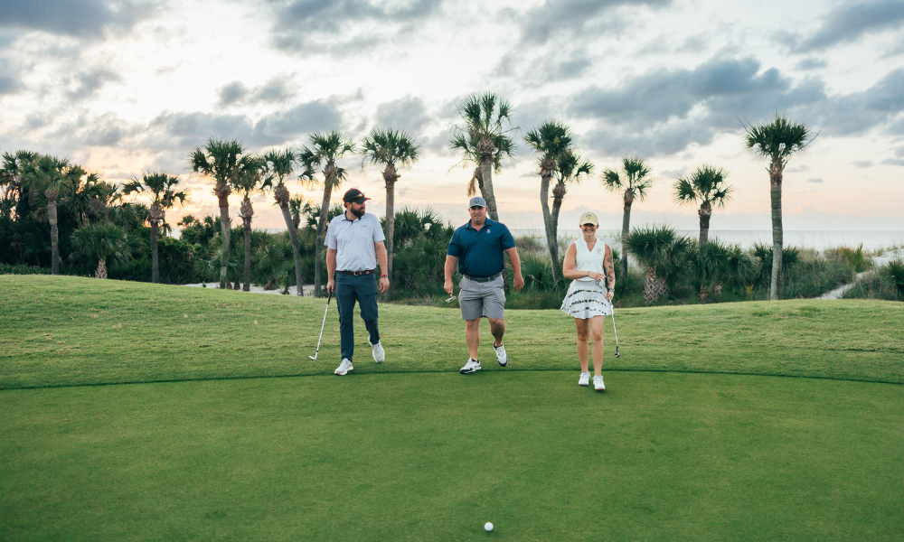 a group of people walking on a golf course