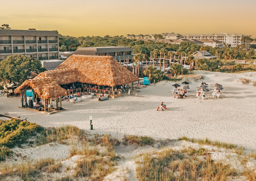 a beach with a hut and people sitting on chairs and umbrellas