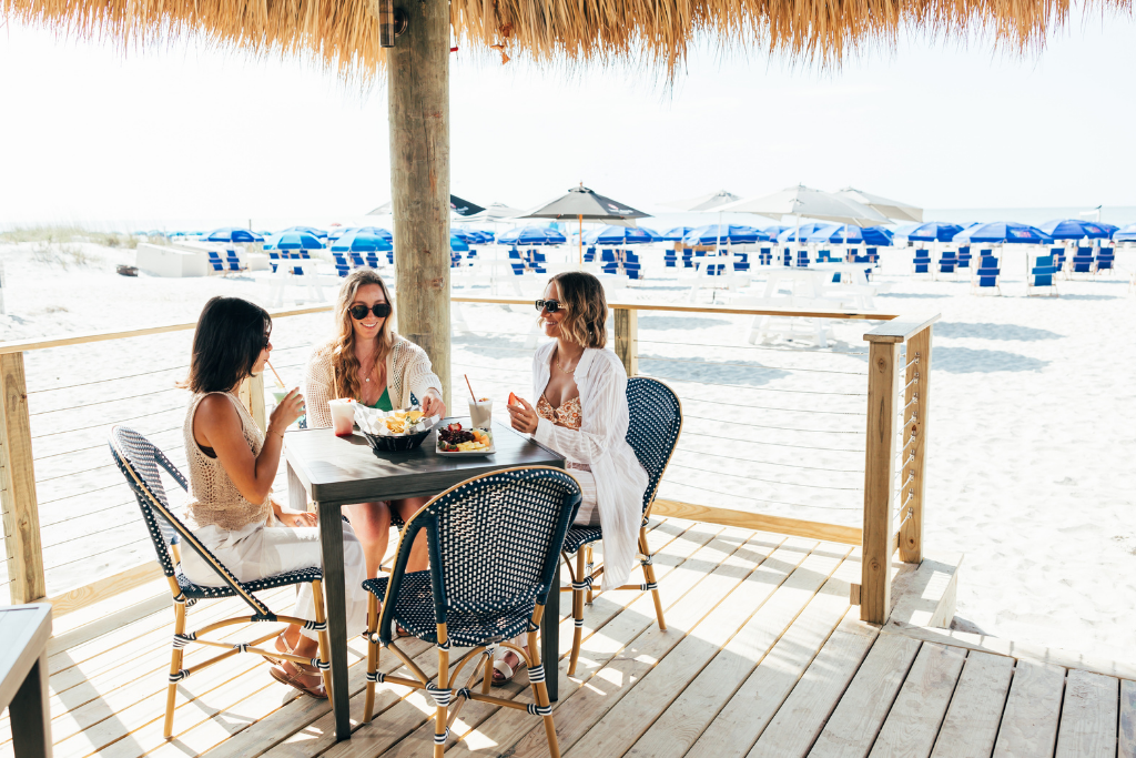 a group of women sitting at a table on a beach