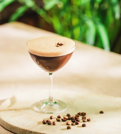 a glass of coffee with coffee beans on a table