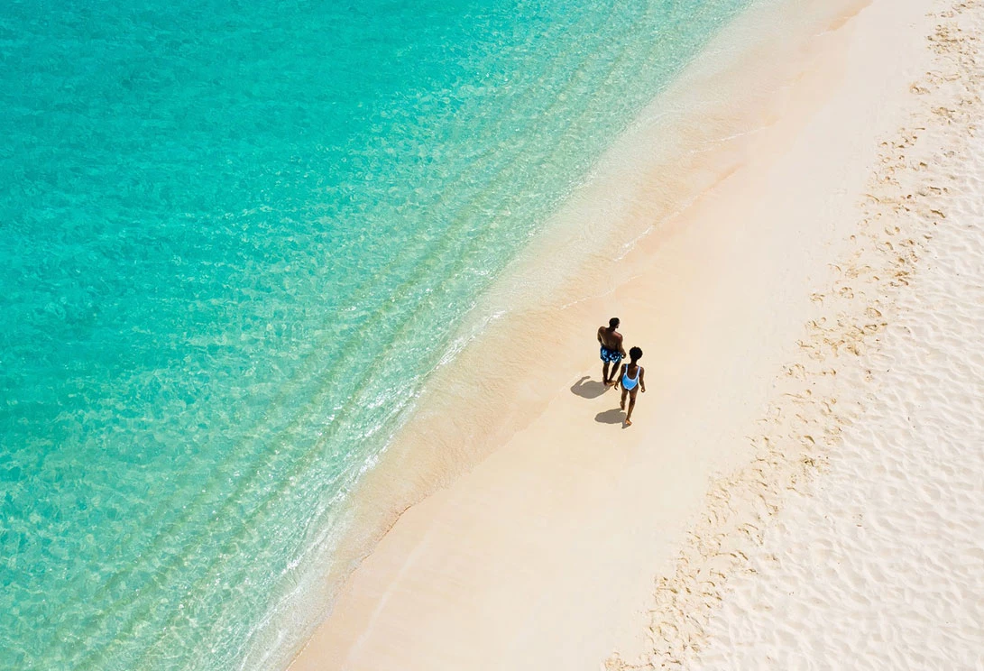 couple walking on white sand beaches