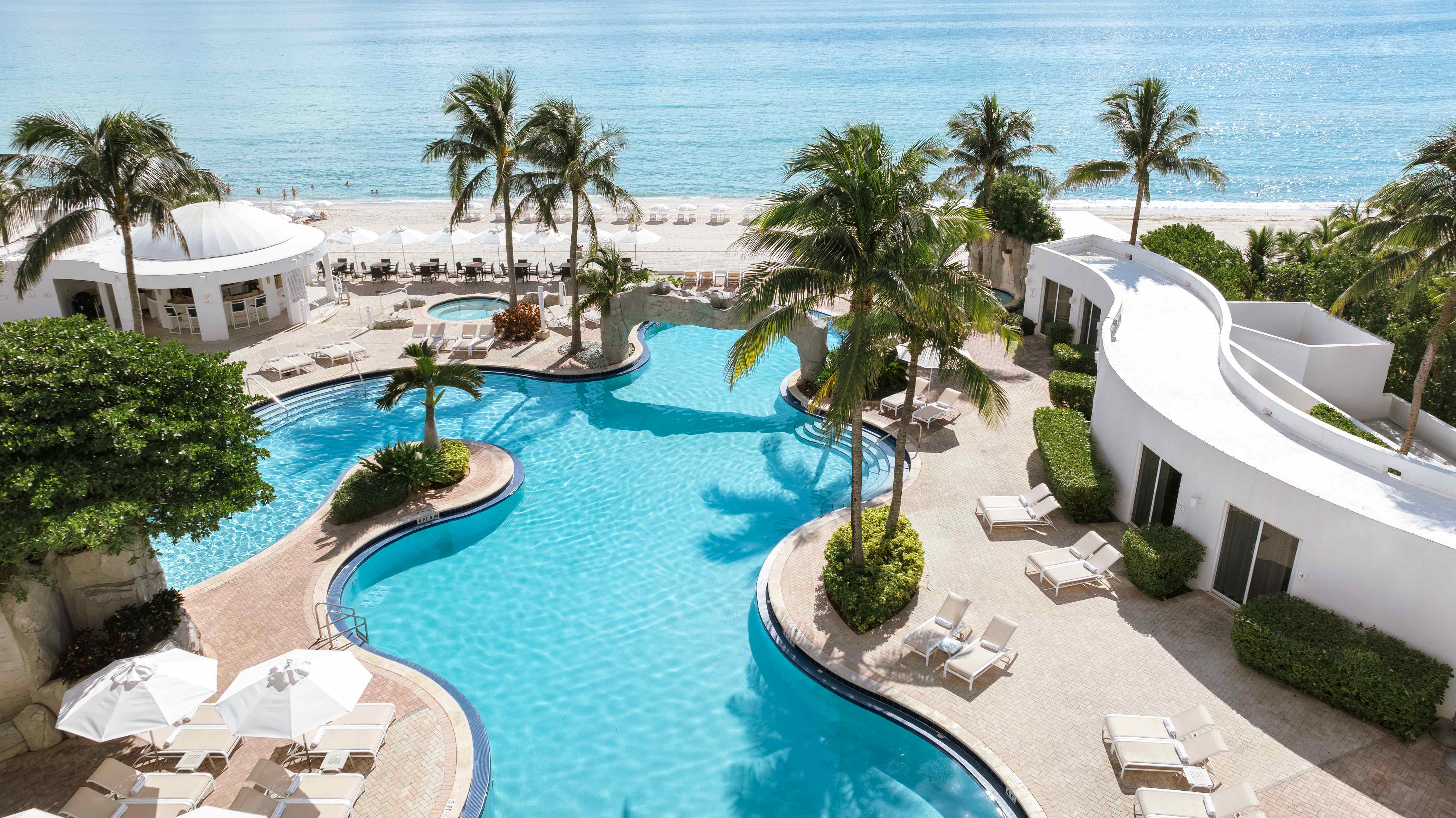 a swimming pool with palm trees and a beach