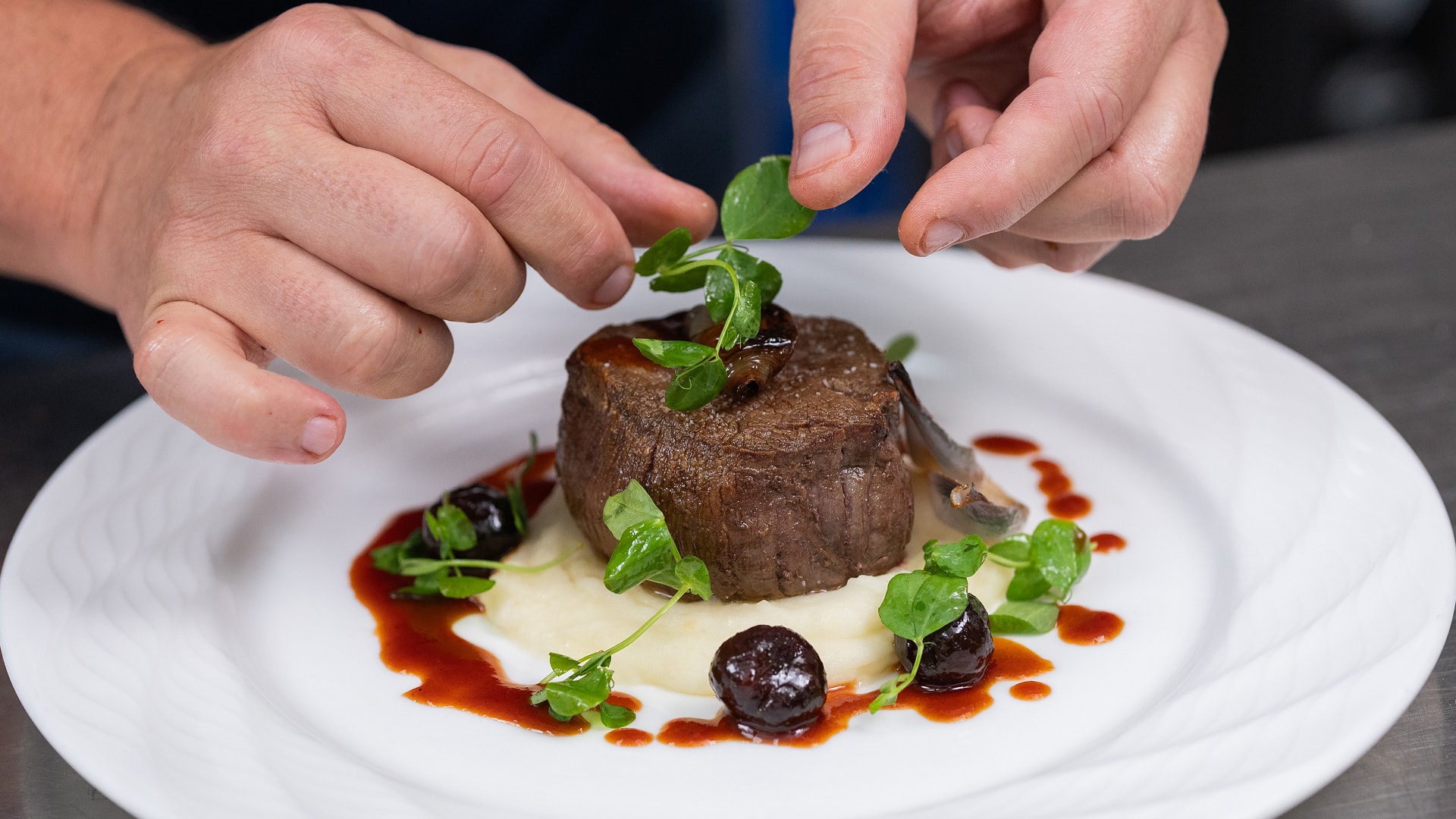 a person's hands decorating a piece of meat