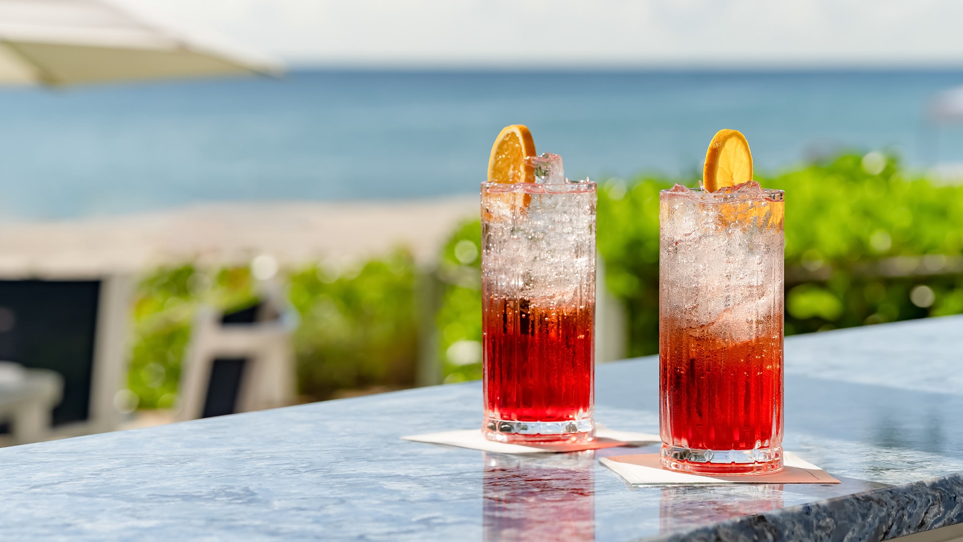 two glasses of red and orange drinks on a table