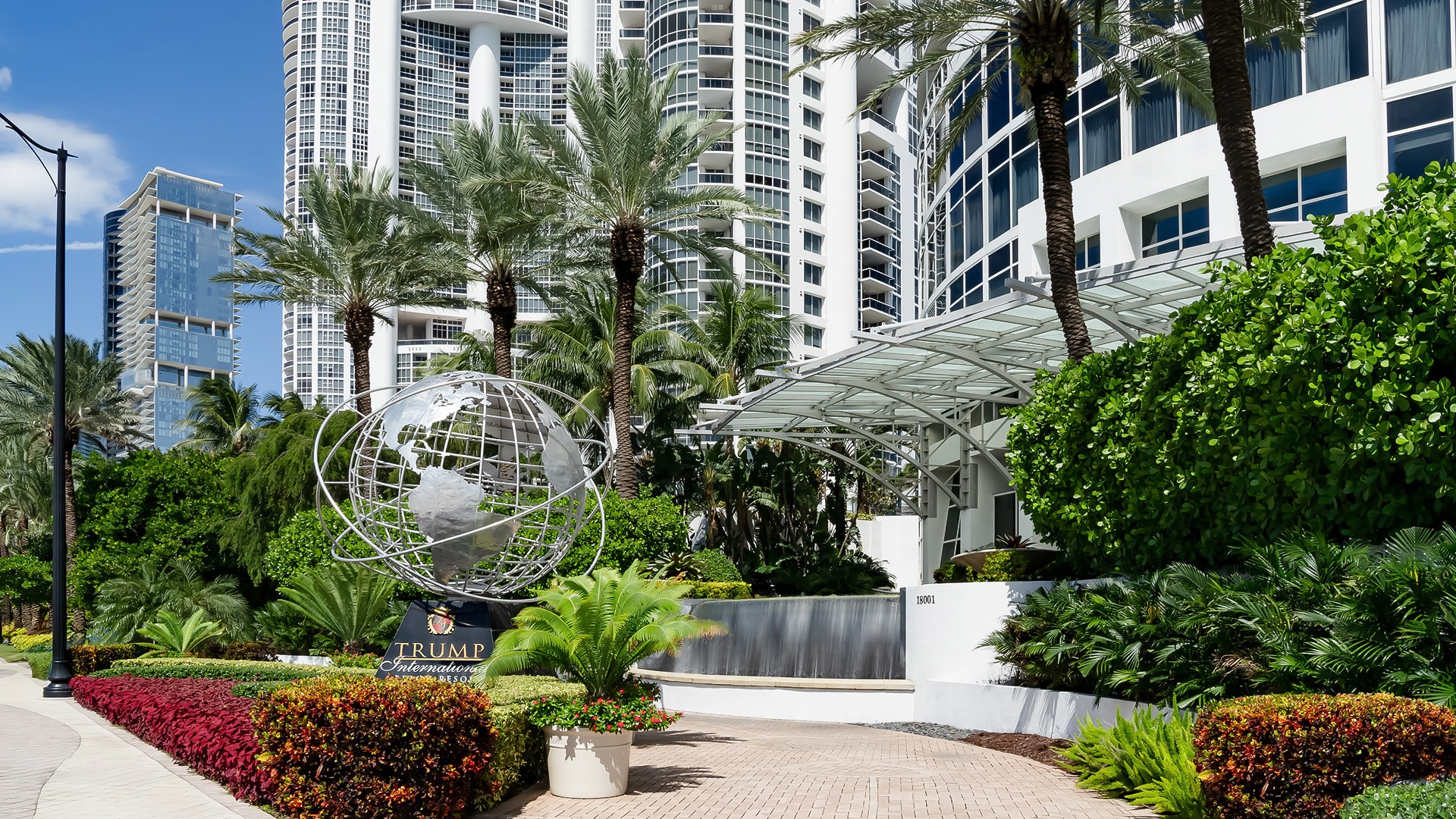 a building with palm trees and a statue of a globe