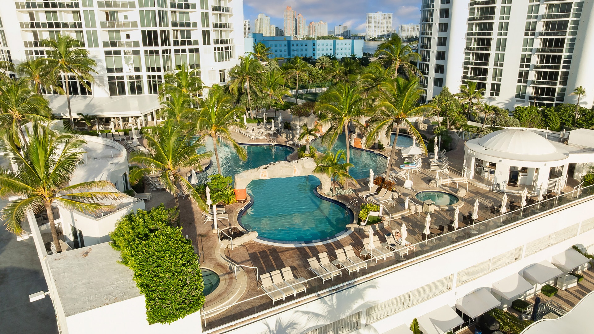 a swimming pool with palm trees and a building in the background