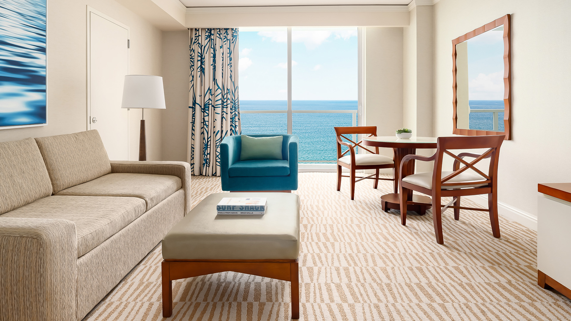 a living room with a table and chairs and a table with a view of the ocean