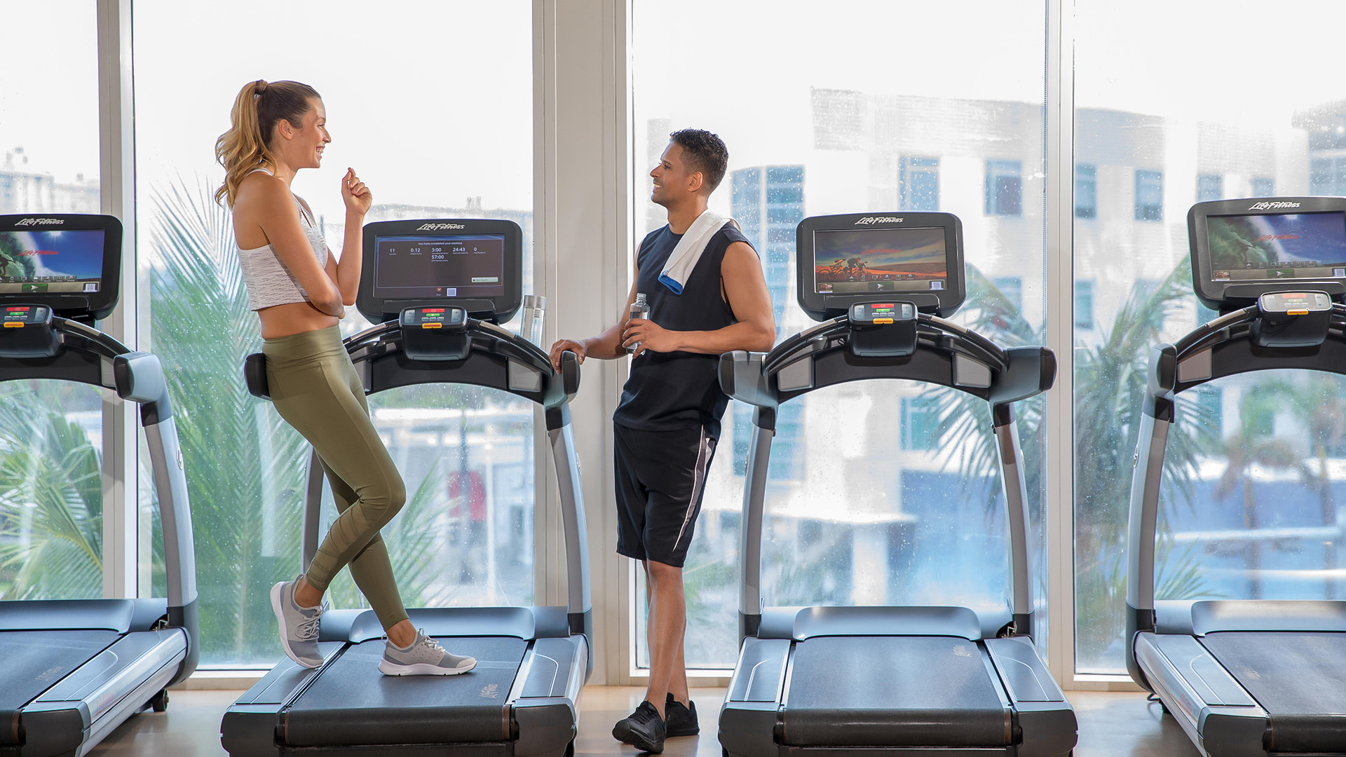 a man and woman standing on treadmills