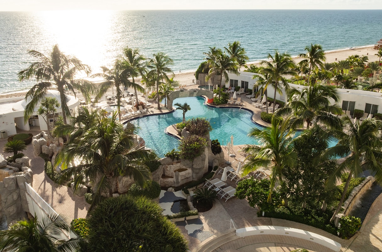 a swimming pool with palm trees and a beach