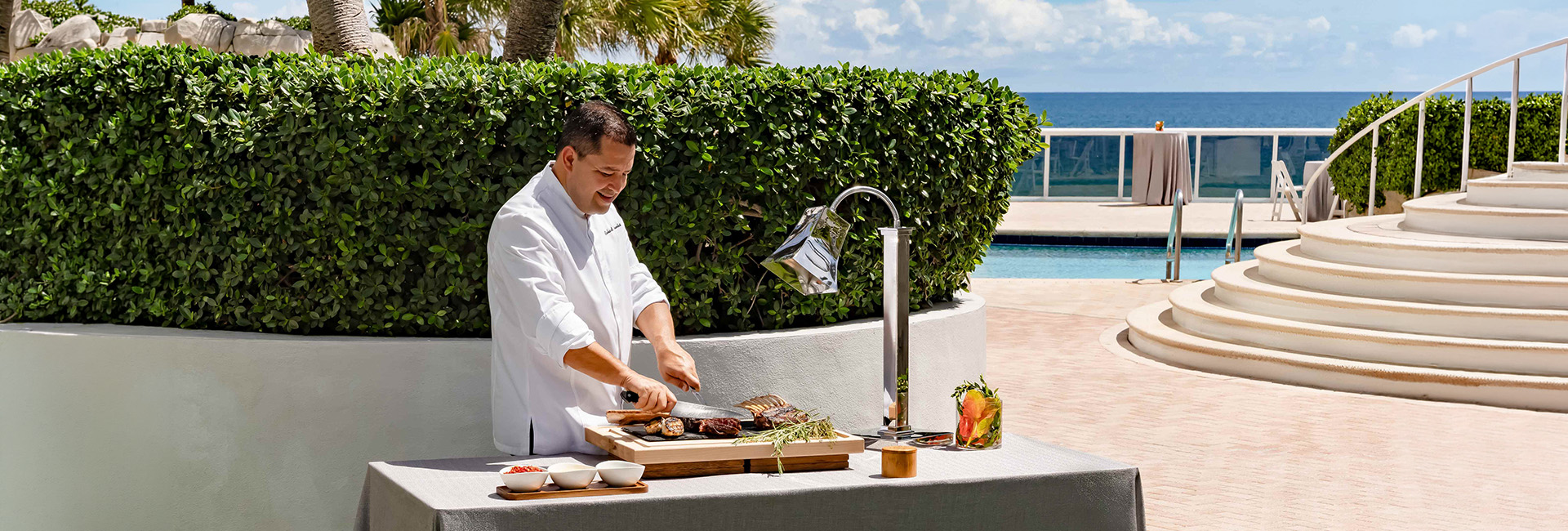 a man in a white shirt cooking meat on a table