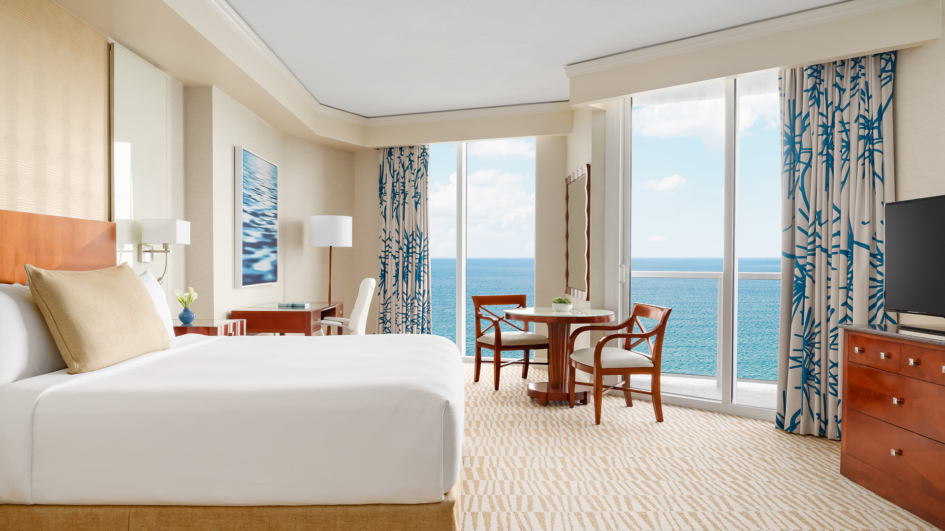 a room with a bed and chairs and a table and chairs overlooking the ocean