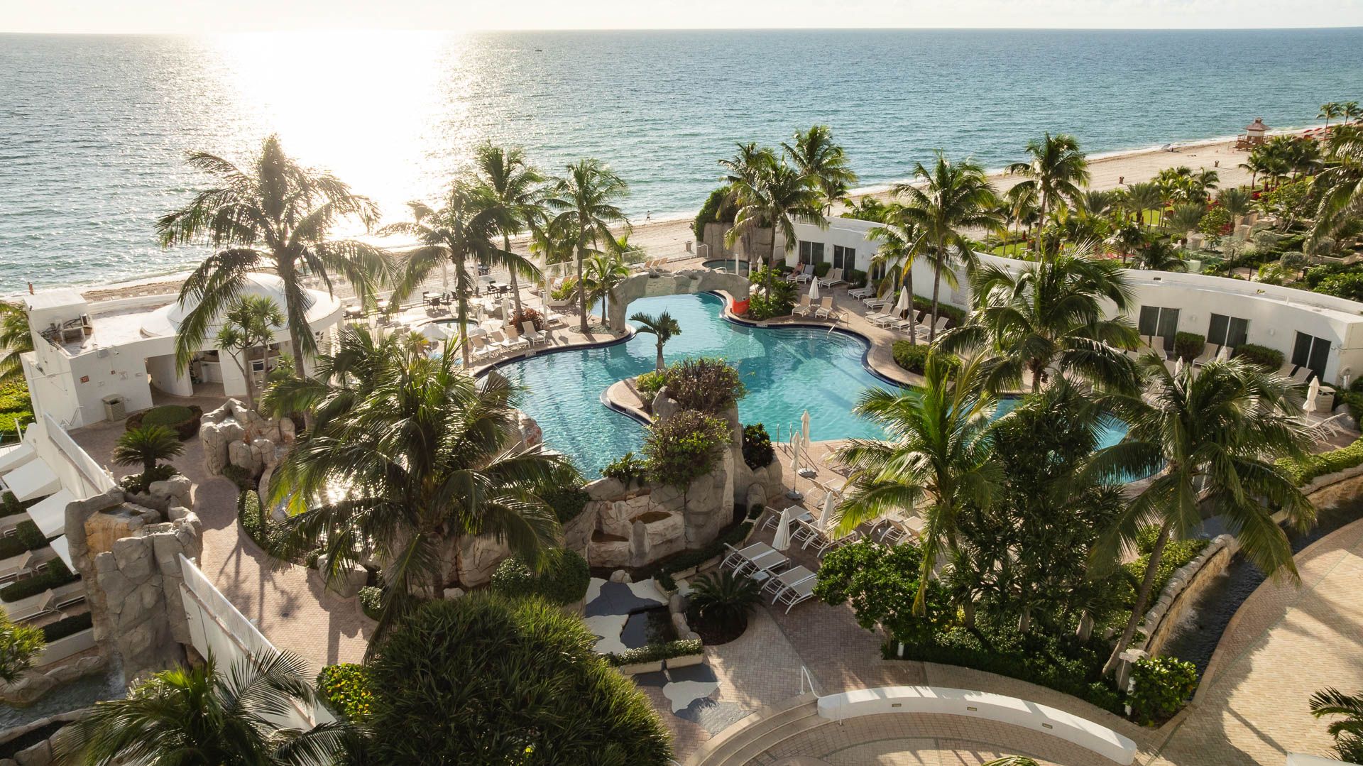 a swimming pool with palm trees and a beach