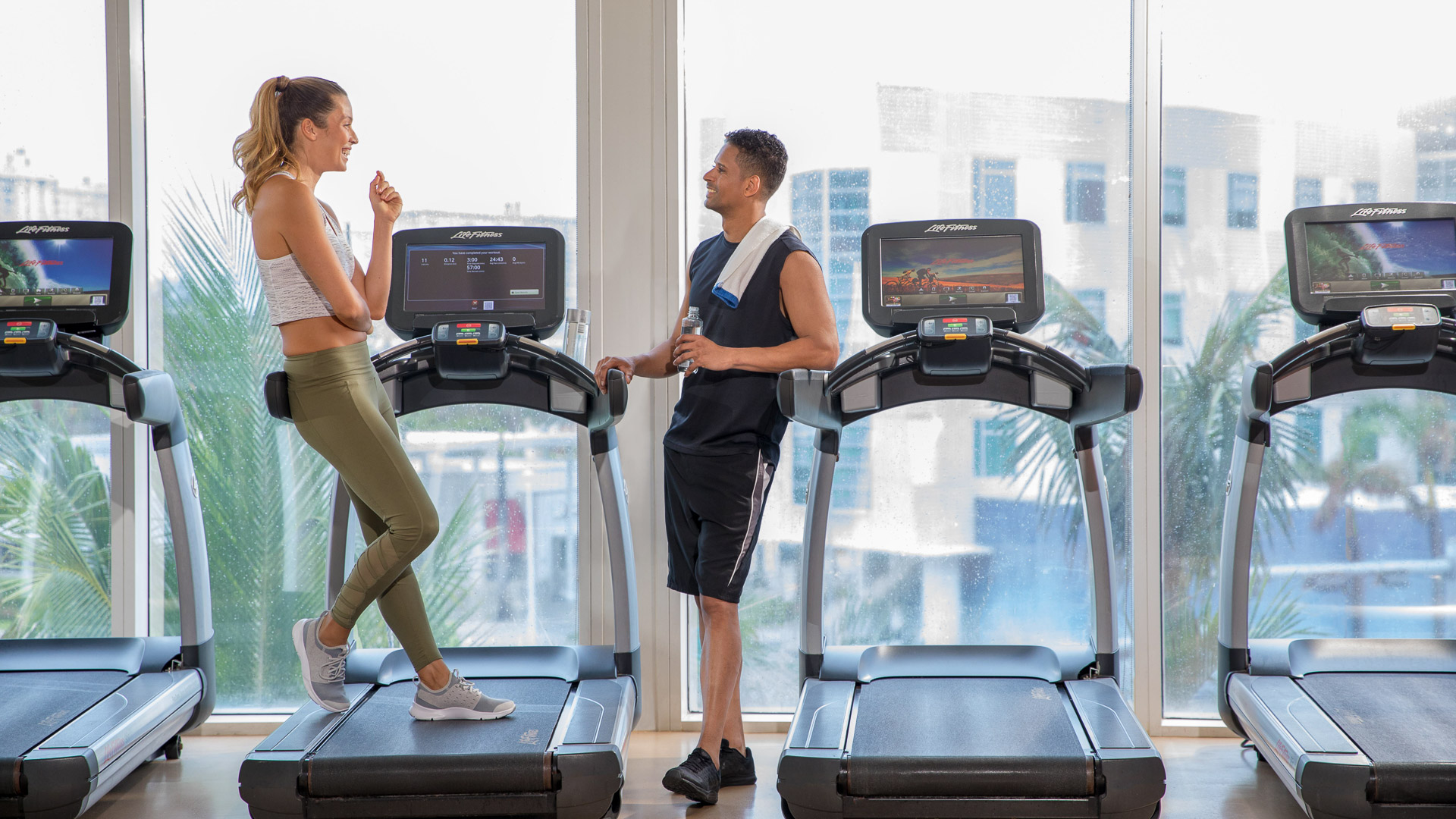 a man and woman standing on treadmills