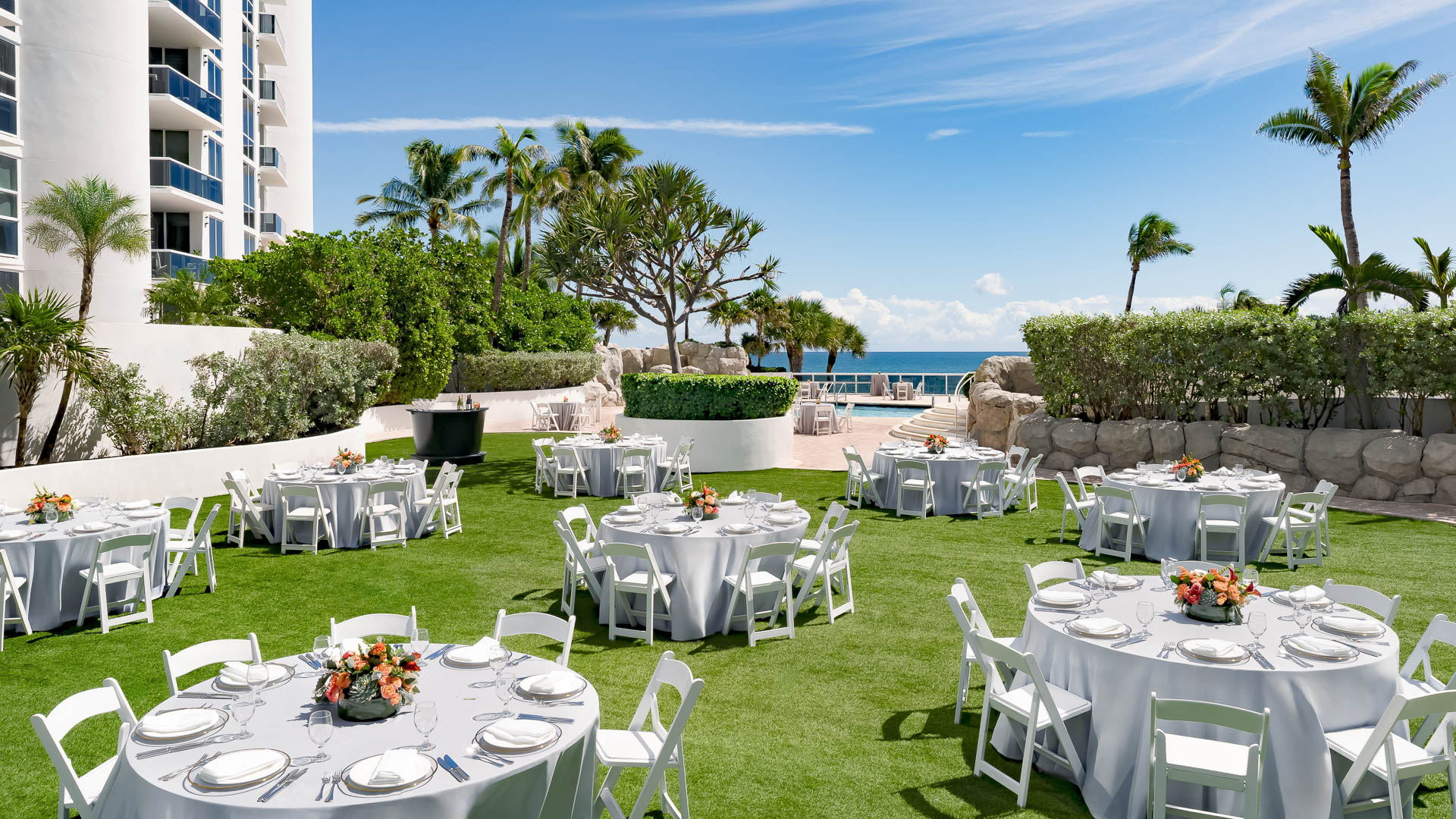 a group of tables set up on a lawn with white tables and chairs