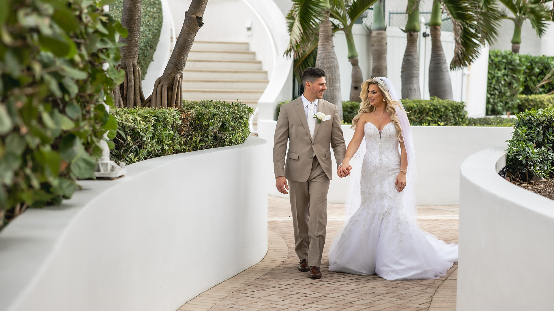 a man and woman in wedding attire walking down a brick walkway