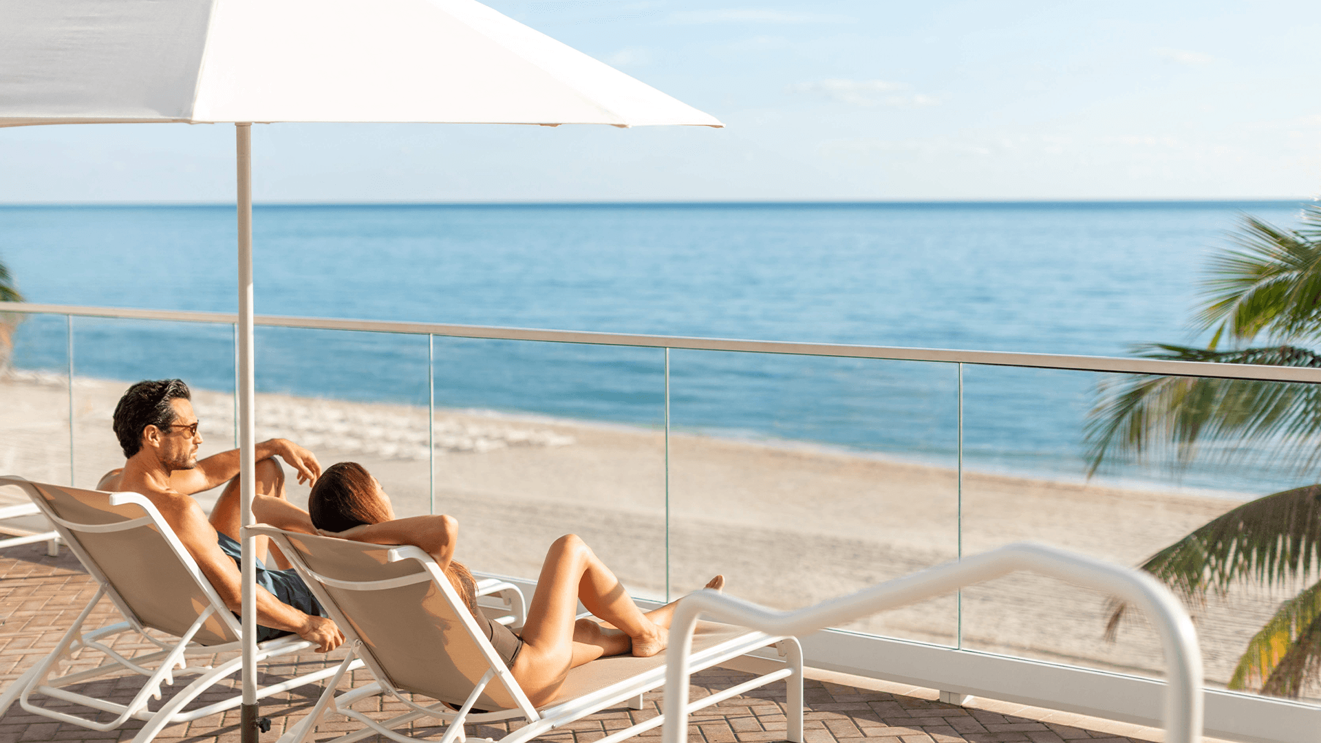 a man and woman sitting on a deck chair on a beach