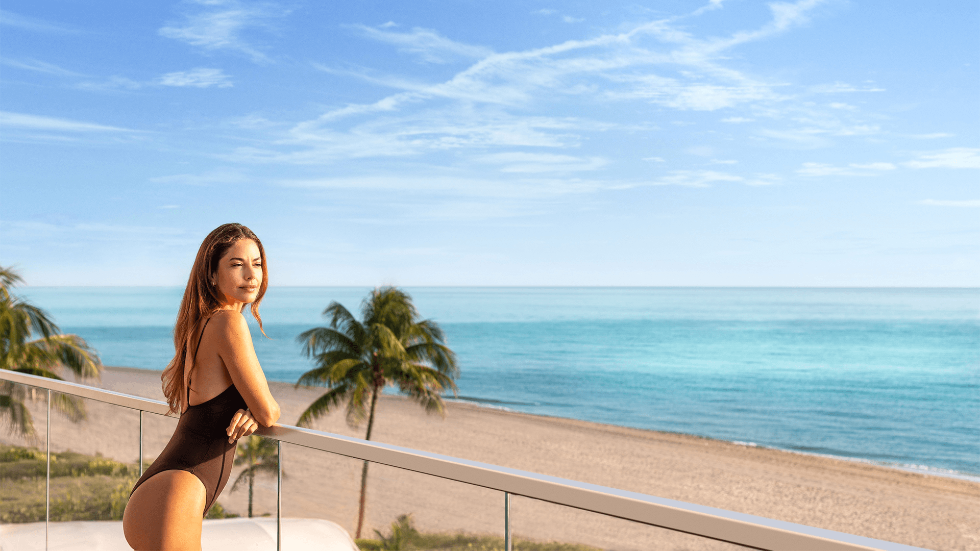 a woman leaning on a railing overlooking a beach