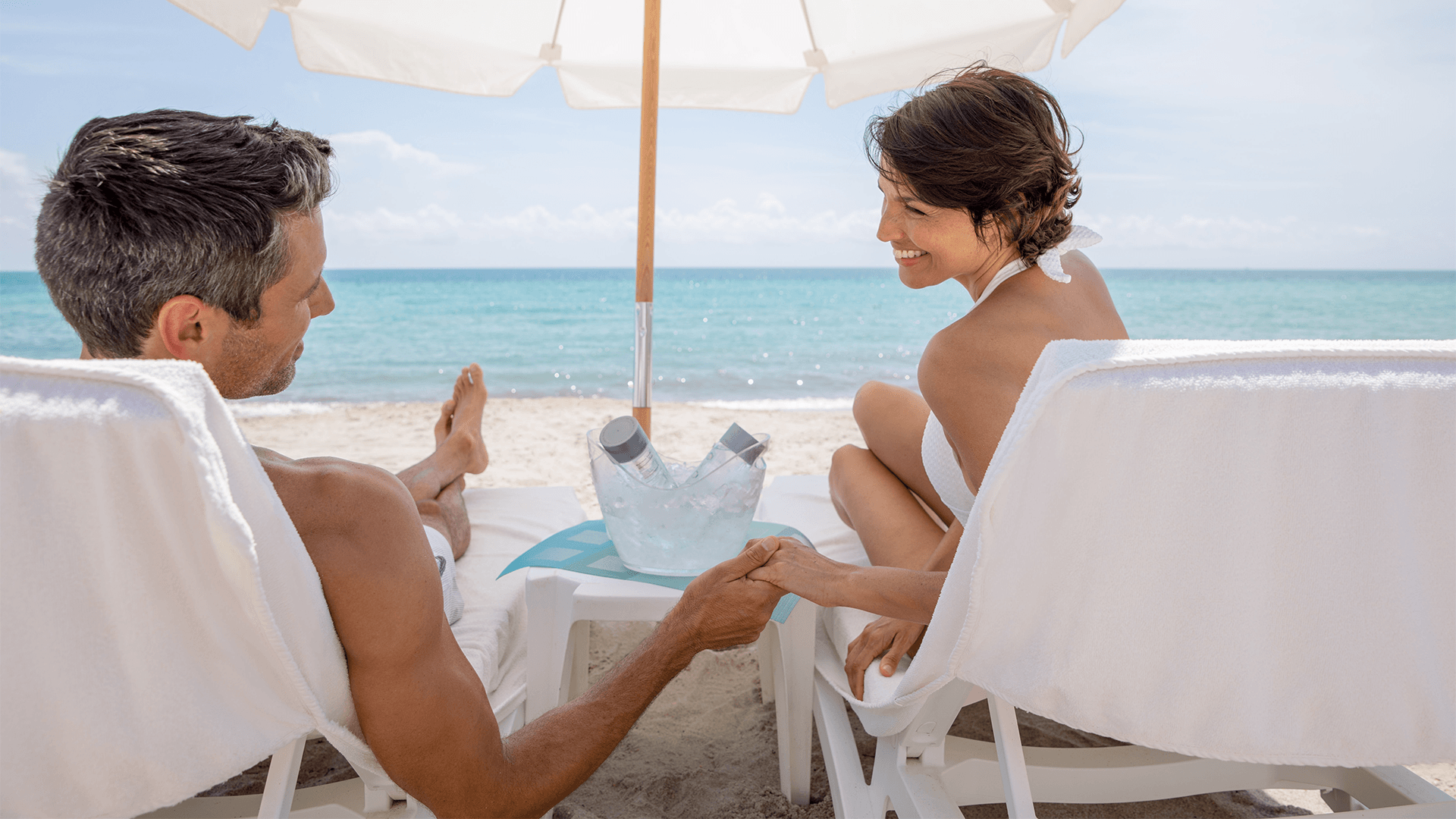 a man and woman sitting on chairs at a beach