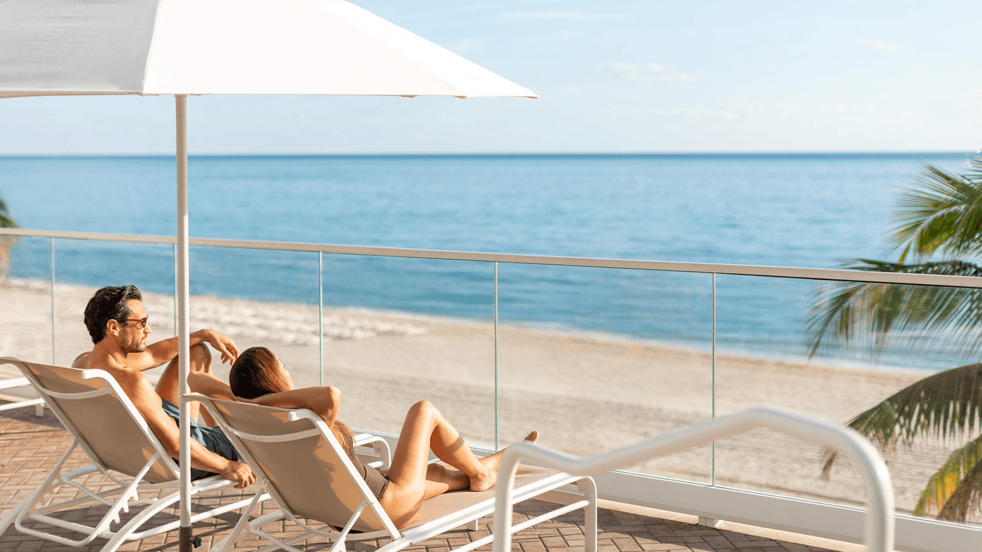 a man and woman sitting on a deck chair on a beach