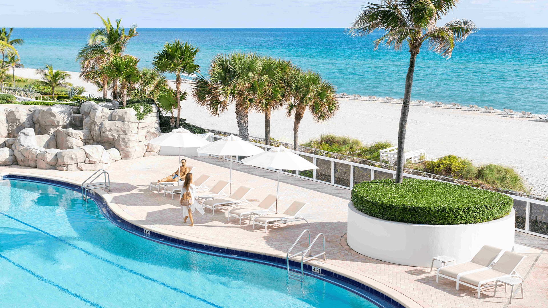 a pool with palm trees and people by it
