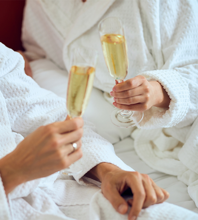 a couple of people in white robes holding champagne glasses