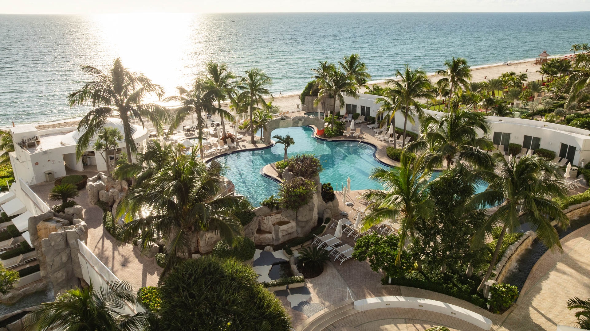 a swimming pool with palm trees and a beach