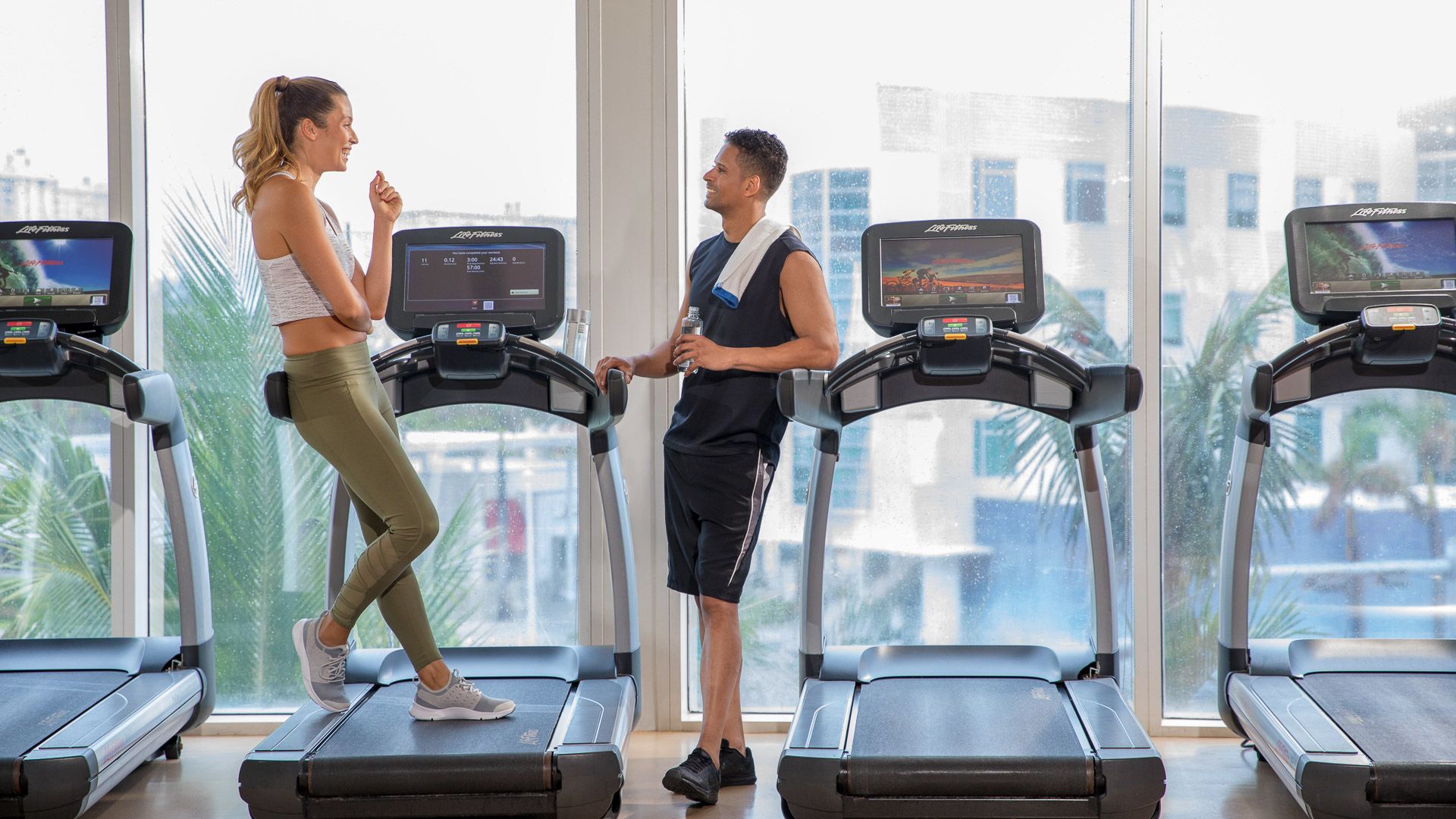 a man and woman standing on treadmills