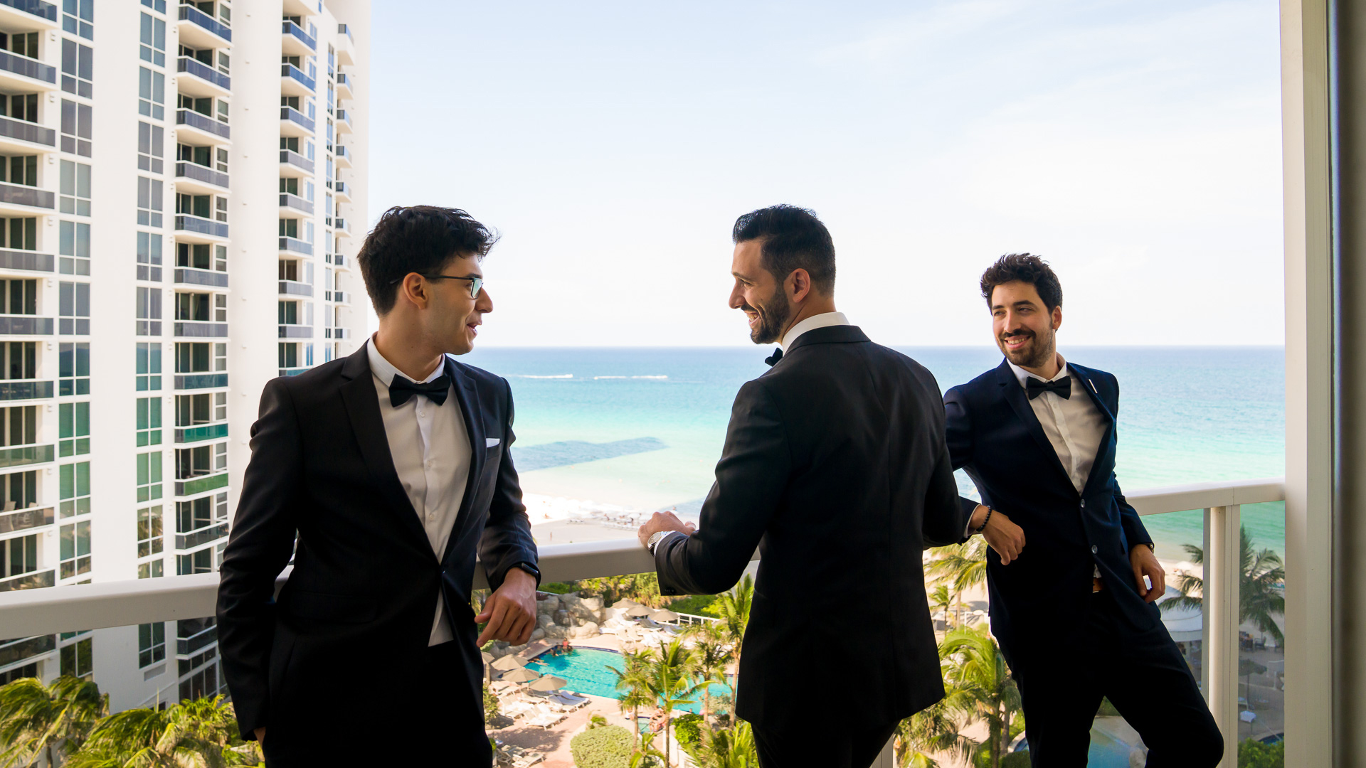 a group of men in suits standing on a balcony overlooking a body of water