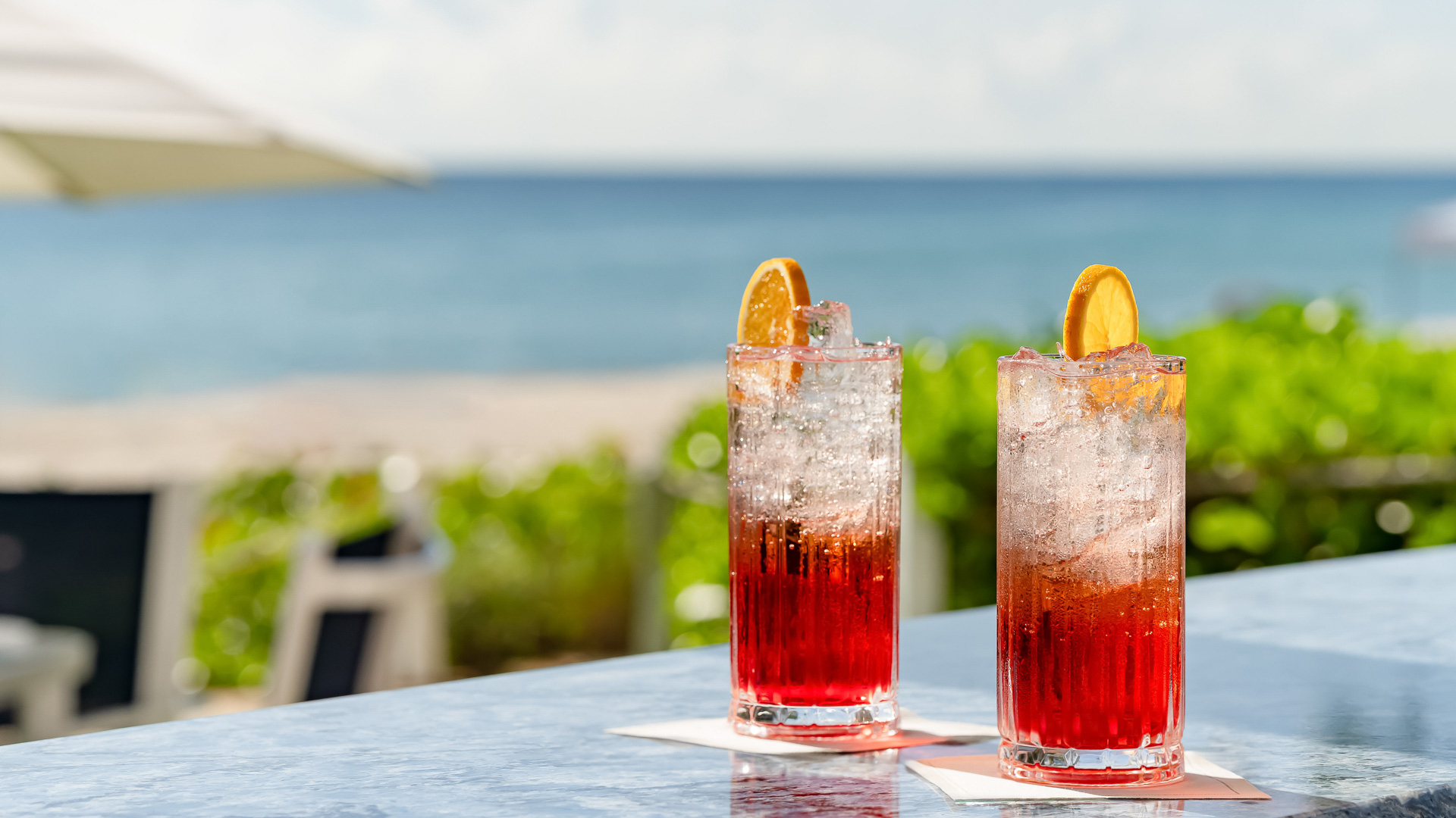 two glasses of red and pink drinks on a table